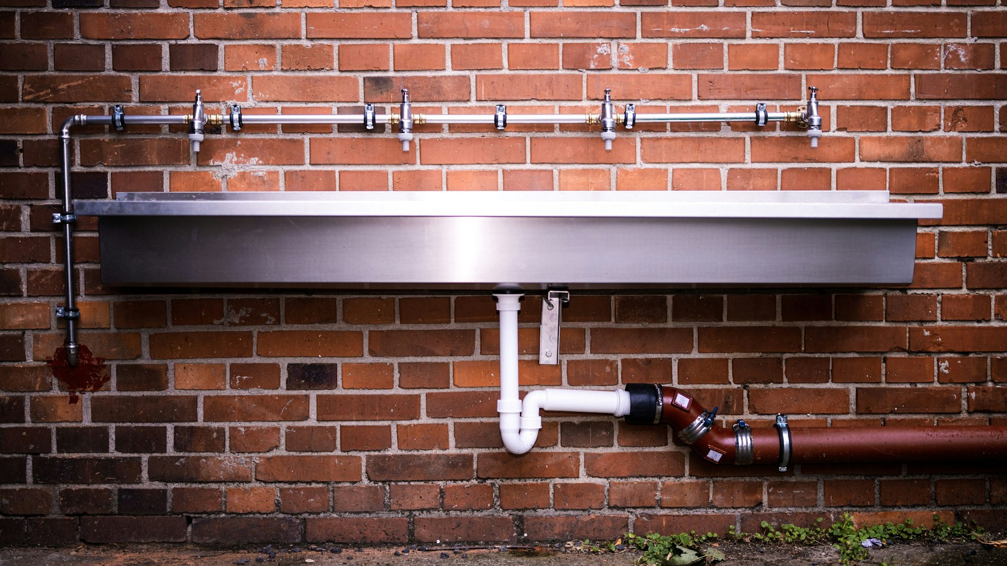 Ein Metallwaschbecken mit mehreren Wasserhähnen.