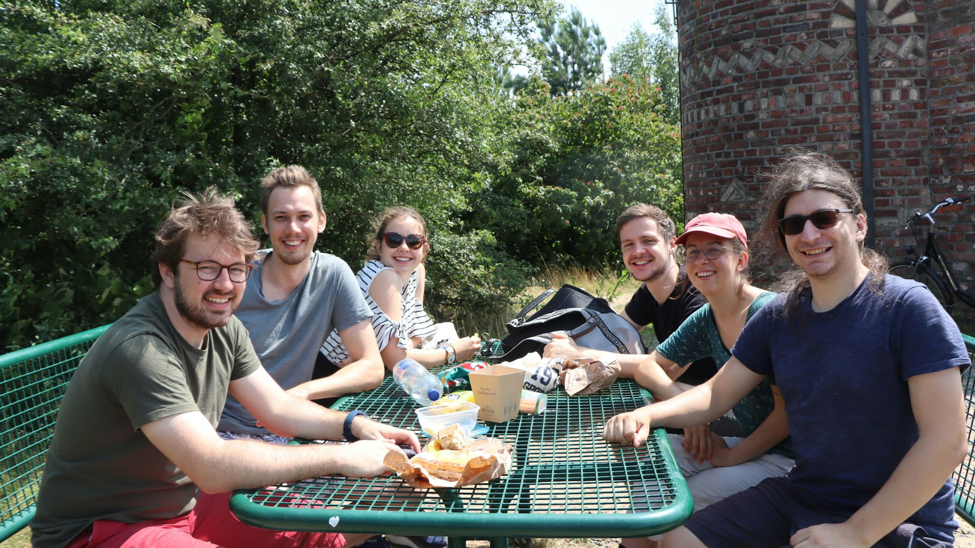 Auf dem Bild sind ehemalige Studenten zu sehen, die ein Picknick an einem Tisch auf der Sophienhöhe machen.