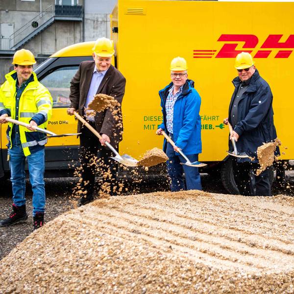 Das Foto zeigt fünf Männer mit Spaten vor einem DHL-Fahrzeug.