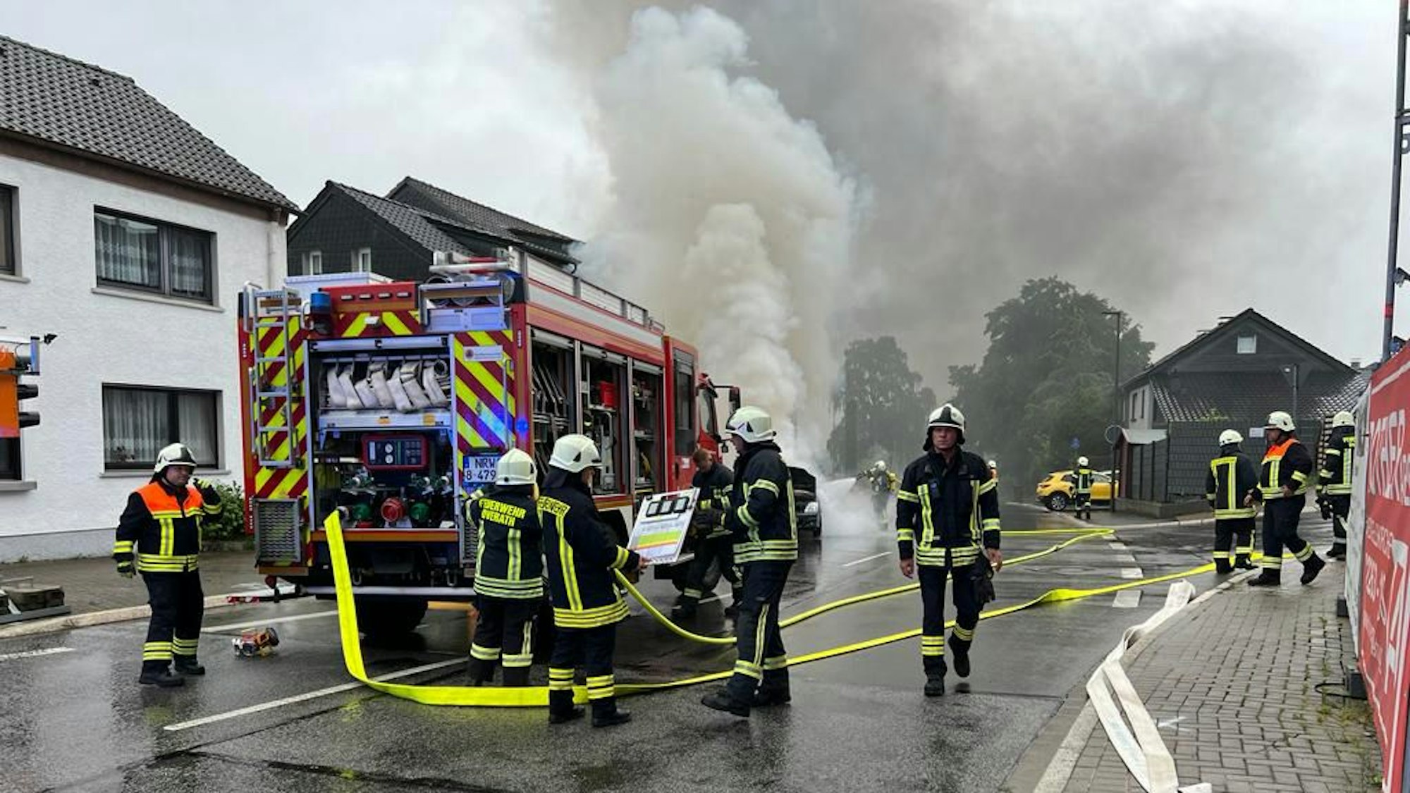 Feuerwehrleute stehen an einem Feuerwehrwagen und löchen den Brand.