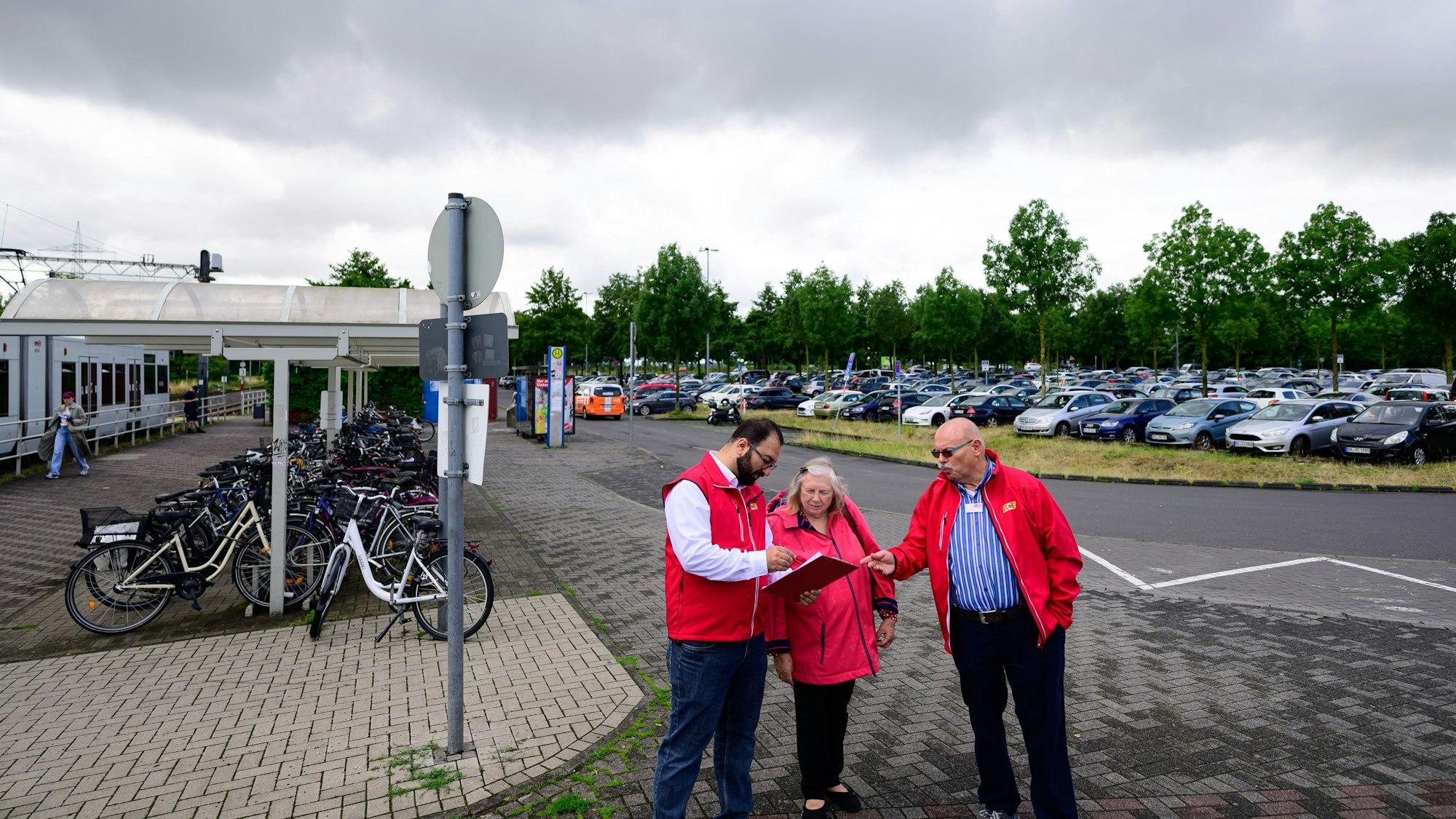 Drei Menschen mit einem Klemmbrett auf einem Parkplatz.