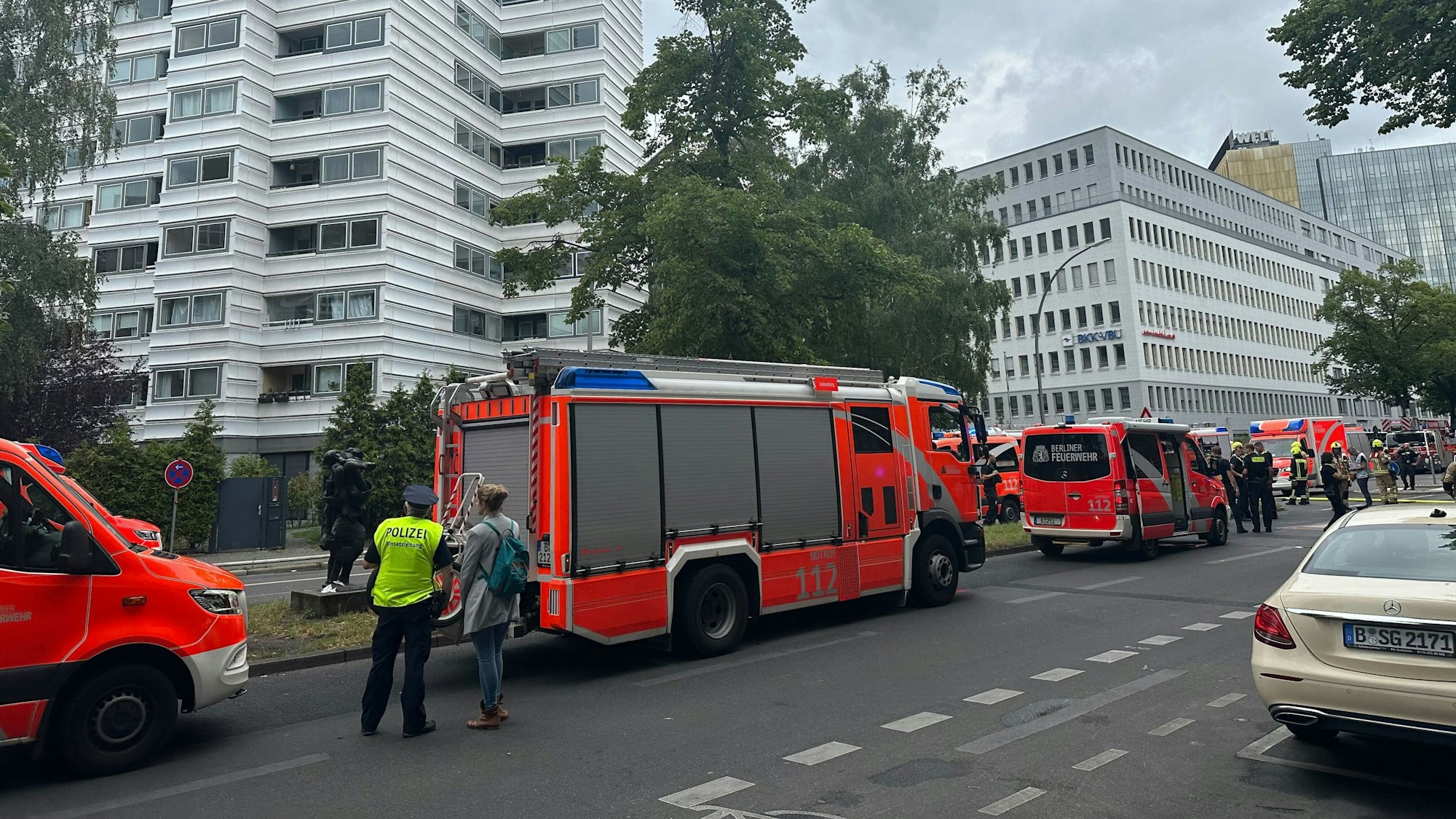 Einsatzkräfte der einem Hochhaus stehen vor einem Hochhaus auf der Straße.