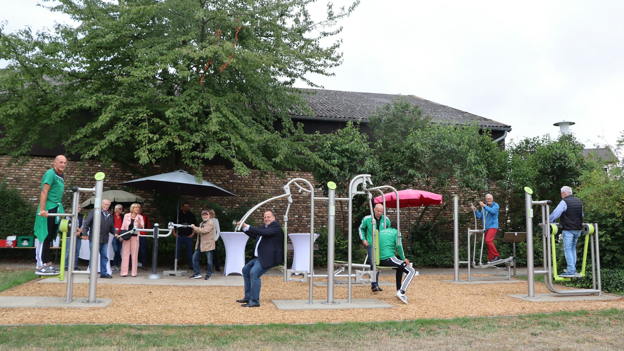 Einige Männer machen Übungen an Fitnessgeräten im Freien.