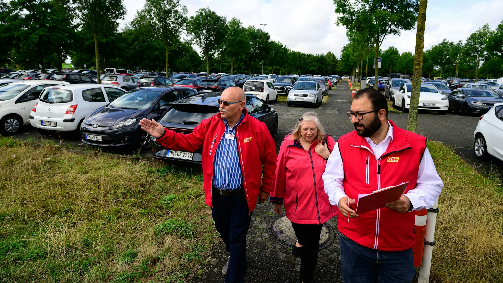 Drei Menschen mit einem Klemmbrett auf einem Parkplatz.