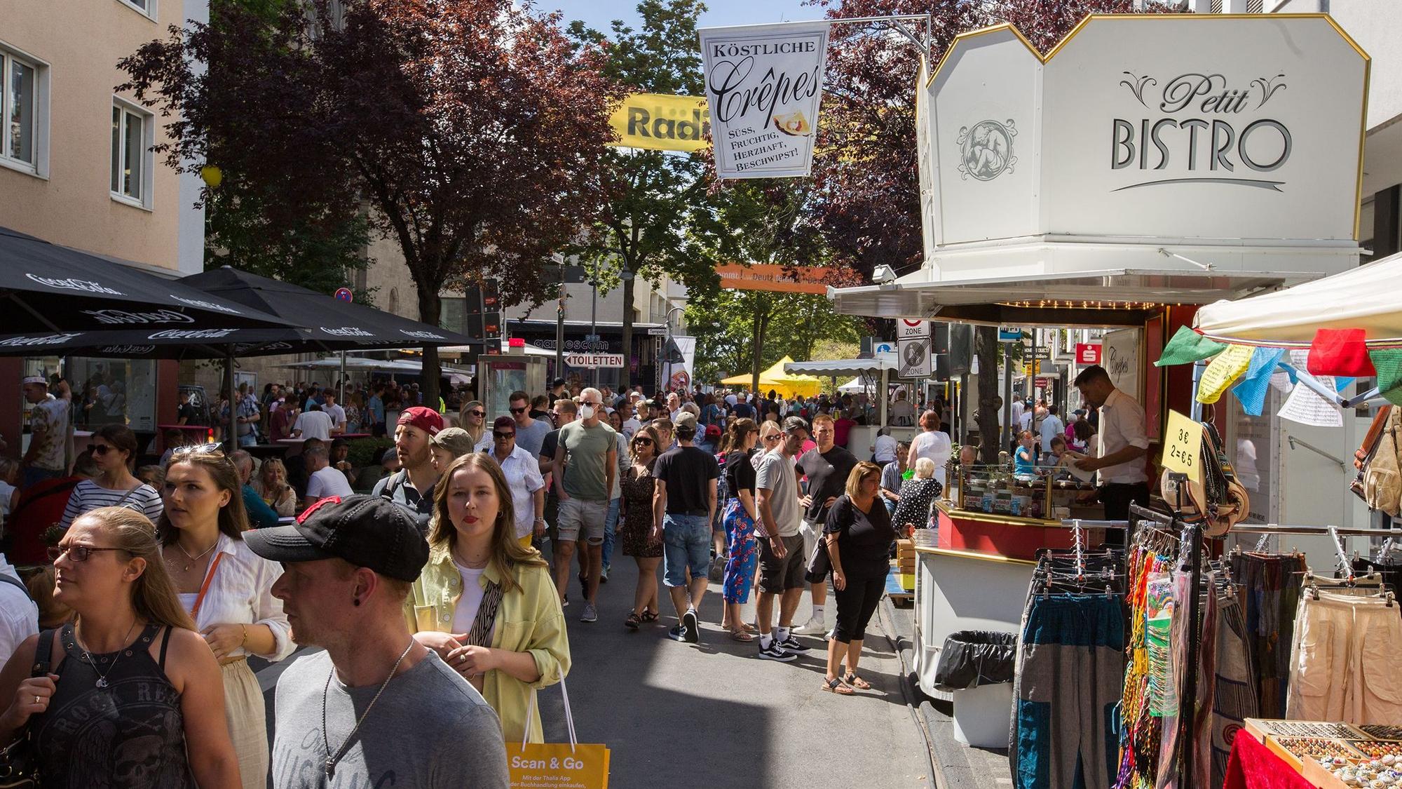 Viele Menschen laufen über eine von Essensständen gesäumte Straße in Deutz.