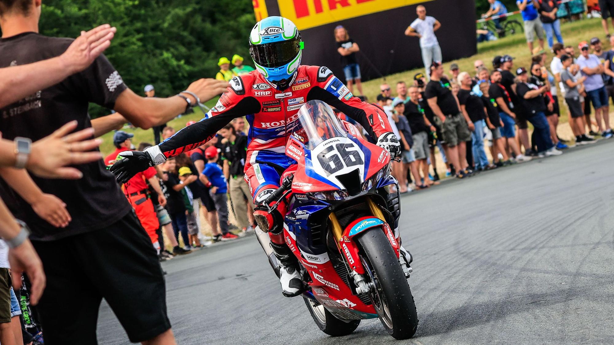 Florian Alt klatscht nach seinem ersten Sieg in Schleiz die Fans ab.
