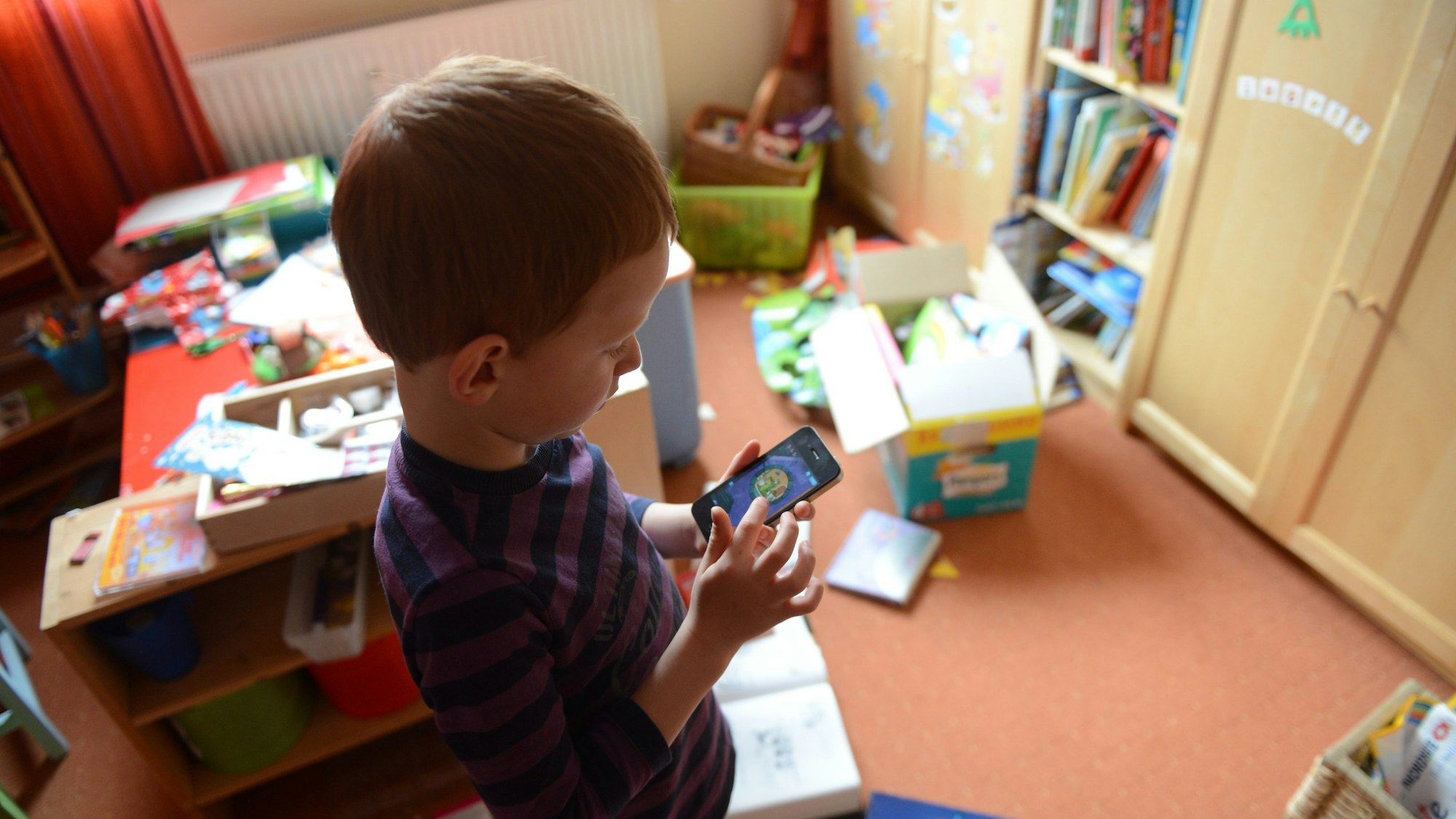 ARCHIV - 09.04.2012, Berlin: ARCHIV - ILLUSTRATION - Ein Junge spielt in seinem Kinderzimmer auf einem Smartphone ein Computerspiel, aufgenommen am 10.04.2012 in Berlin. Viele Kinder spielen gerne Spiele auf Smartphones.
Für dein ganz persönliches Hörbuch drückst du den Aufnahmeknopf beim Handy. Dann kannst du von einem gemeinsamen Erlebnis erzählen oder eine Geschichte vorlesen. (zu dpa: «Geschenke in letzter Minute») Foto: Jens Kalaene/dpa - Honorarfrei nur für Bezieher des Dienstes dpa-Nachrichten für Kinder +++ dpa-Nachrichten für Kinder +++