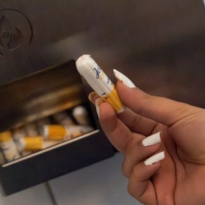 Eine Schülerin hält einen Menstruationsartikel vor einem Menstruationsartikel-Spender.