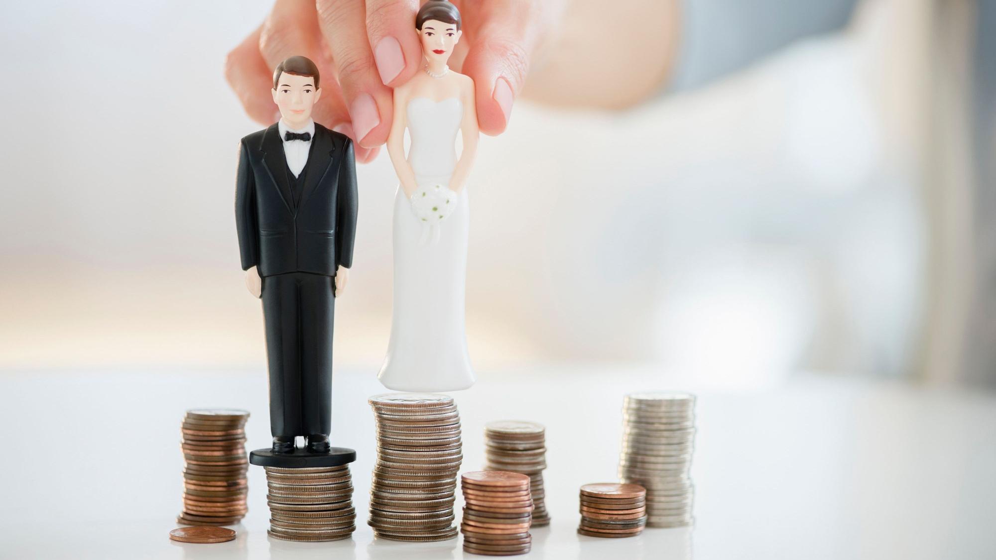 Nahaufnahme von Hochzeitstortenfiguren auf Münzstapeln.