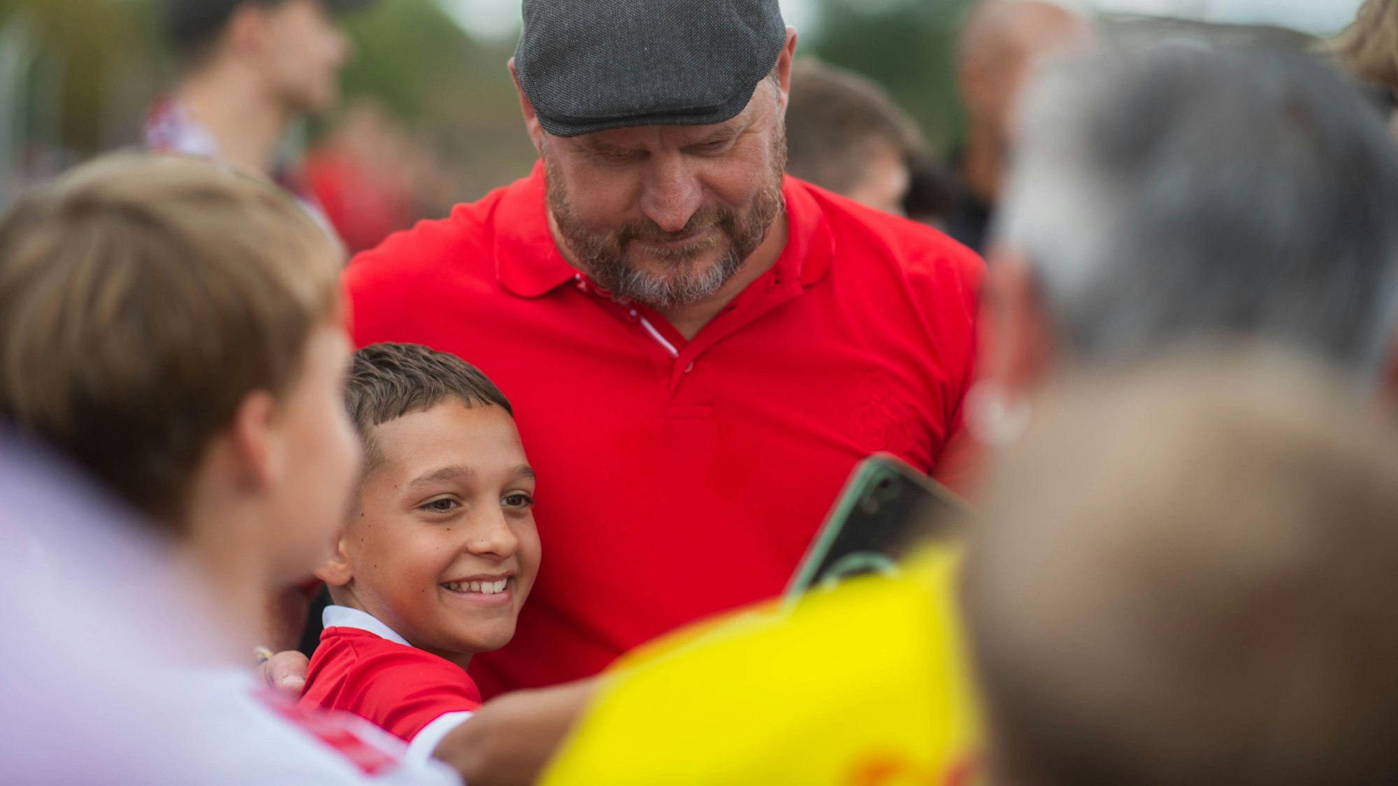 Ein junger Fan macht ein Selfie mit Steffen Baumgart, dem Trainer des 1. FC Köln.