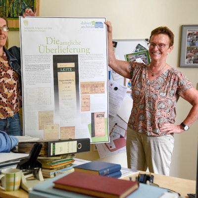 Das Bild zeigt Susanne Kremmer und Susanne Harke-Schmidt, die die ersten Ergebnisse zur Ausstellung zum Thema Archivarbeit zeigen.