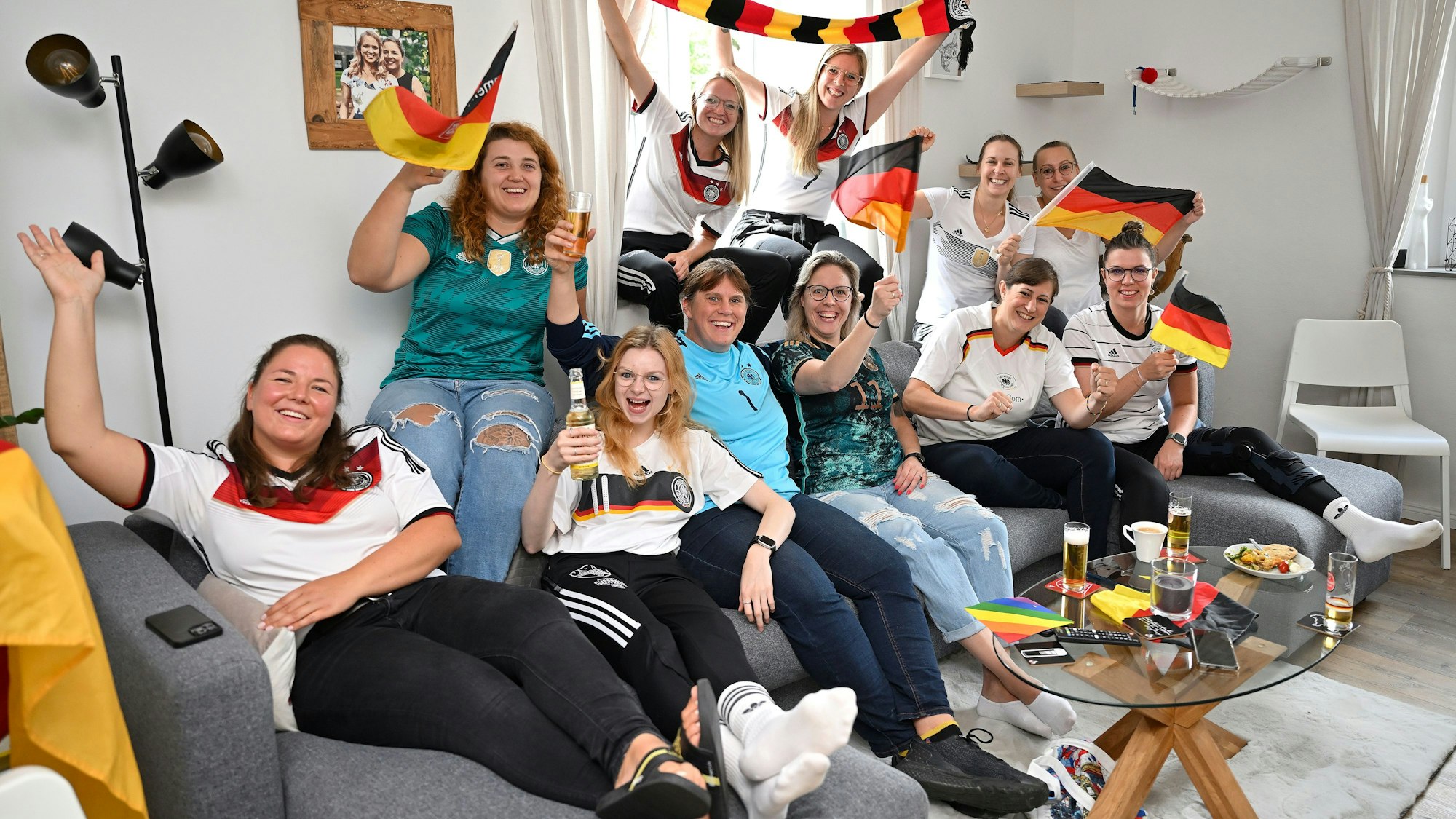 Die Frauen des TUS Marialinden sitzen auf der Couch und schwenken Fahnen.