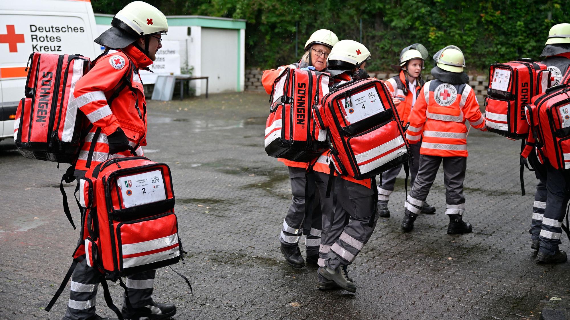 Rettungssanitäter des Deutschen Roten Kreuzes tragen Rettungsrucksäcke zur Einsatzstelle.