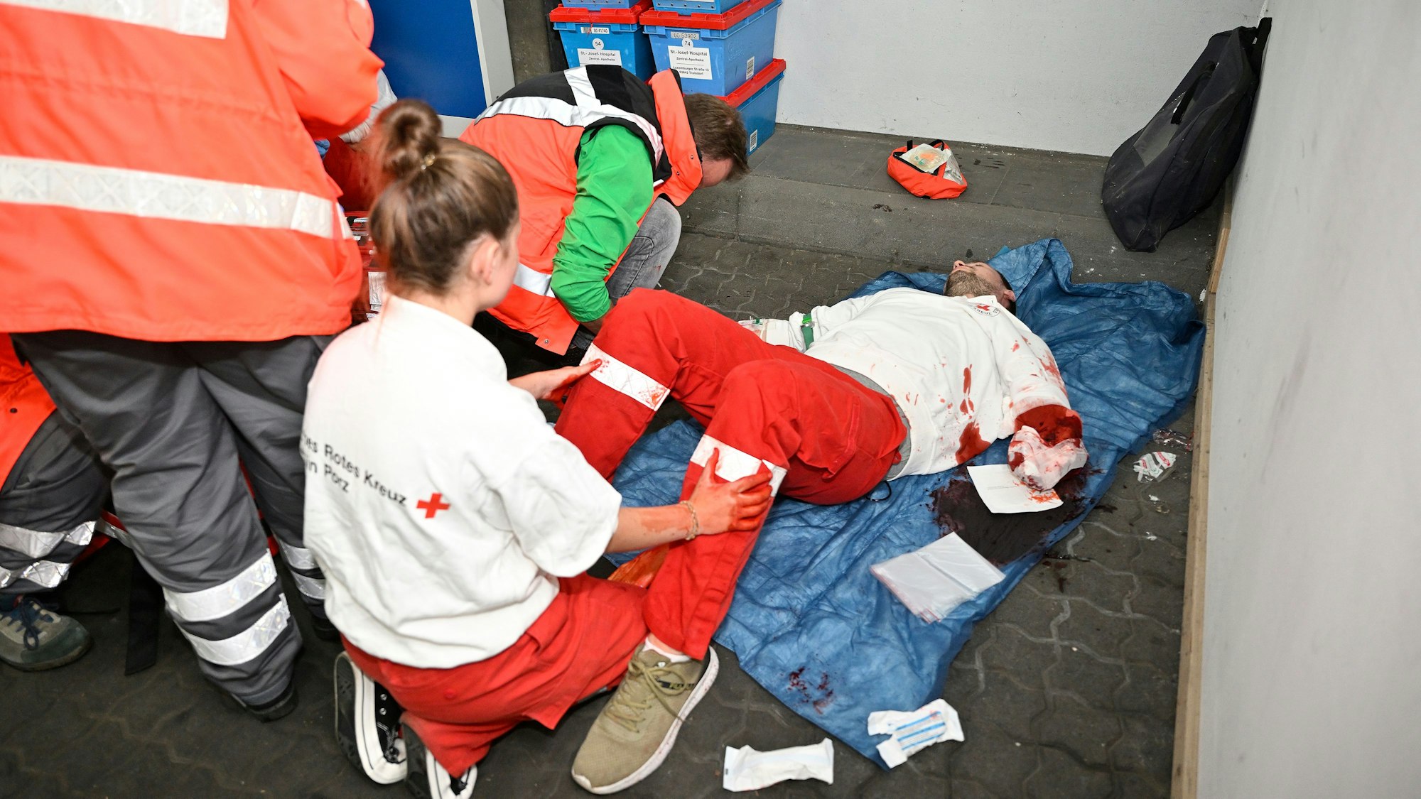 Ein junger Mann liegt im Rahmen einer Einsatzübung mit abgetrenntem Unterarm auf dem Boden und wird behandelt.