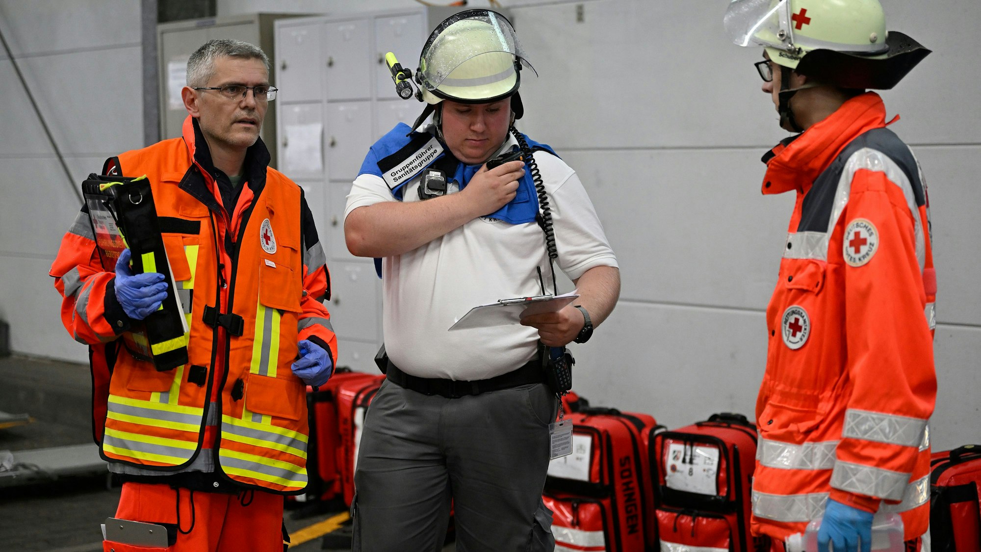 Einsatzkräfte stehen beieinander und besprechen das Vorgehen, einer der Männer bedient ein Funkgerät.