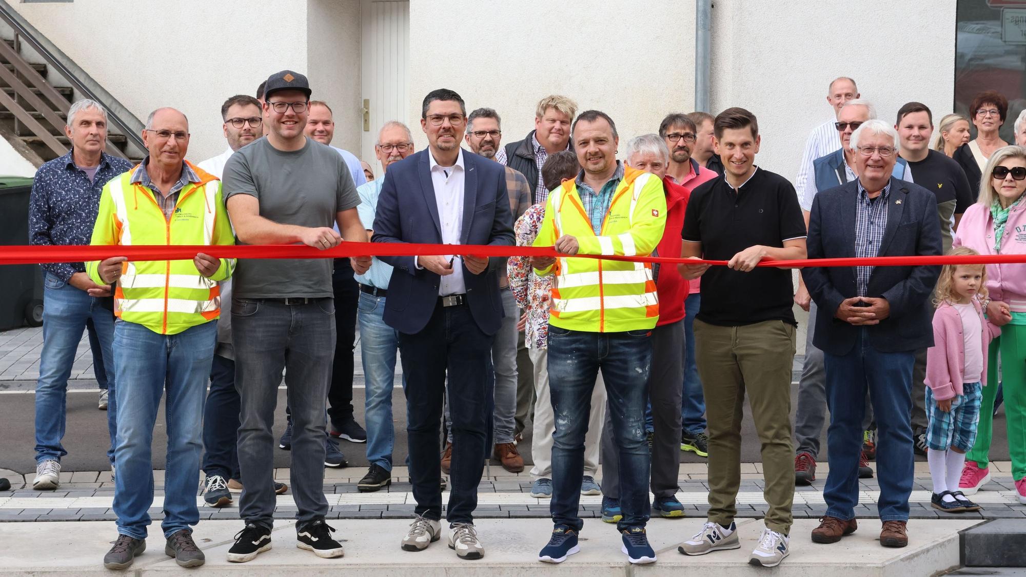 Zu sehen sind mehrere Menschen, die ein rotes band durchschneiden.
