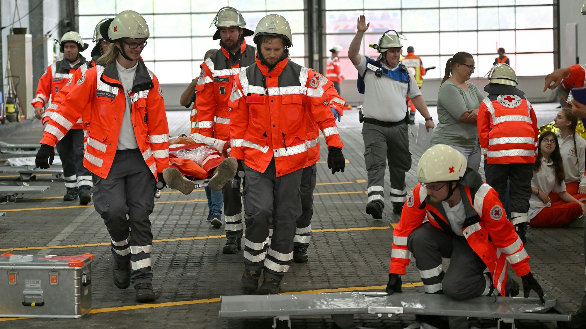 Rettungssanitäter bringen Verletzte auf einer Trage zu einem Behandlungsplatz, Ärzte versorgen Schwerverletzte sofort an Ort und Stelle.