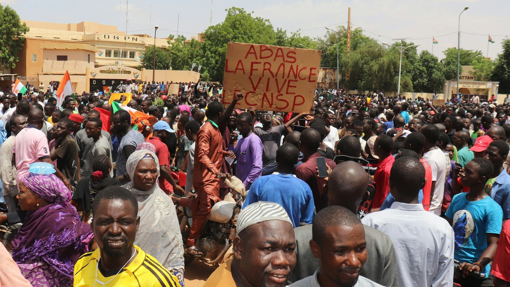 Niger, Niamey: Demonstranten nehmen an einem Marsch zur Unterstützung der Putschisten in der Hauptstadt teil, in der Mitte ein Schild mit der Aufschrift ‚Nieder mit Frankreich, es lebe der CNSP‘ ('Nationaler Rat für den Schutz des Vaterlandes'