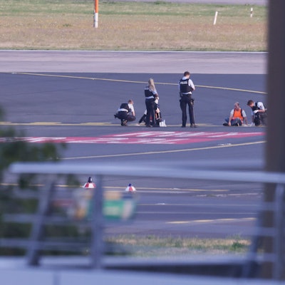 Düsseldorf: Polizisten stehen auf dem Flugfeld und versuchen Aktivisten der Gruppe Letzte Generation am Flughafen vom Asphalt zu lösen, nachdem diese sich festgeklebt hatten.