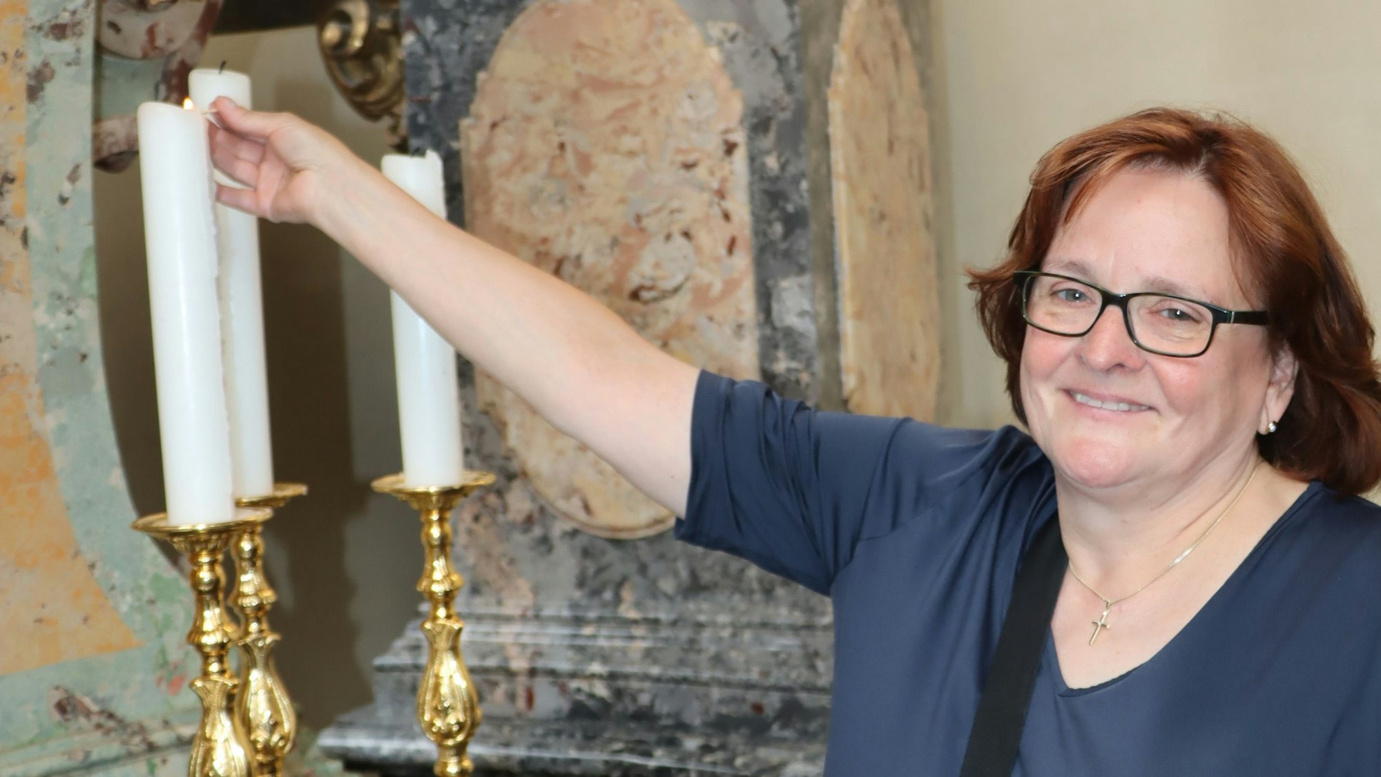 Sakristanin Jutta Heuser zündet eine Kerze an.