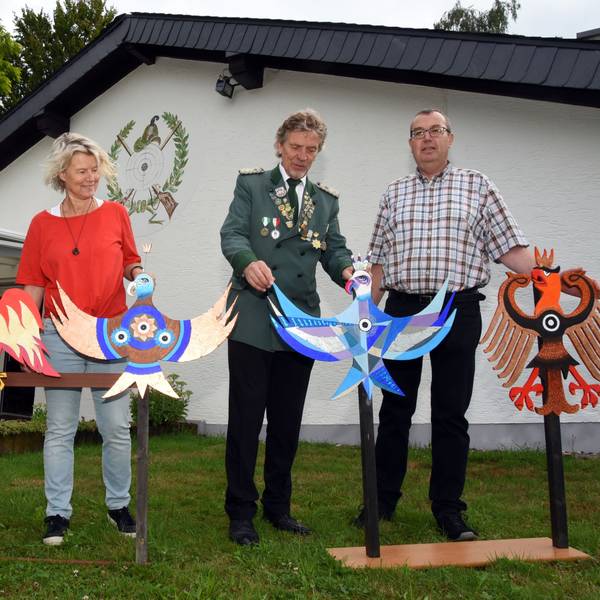 Vier Menschen präsentieren fünf Holzvögel.