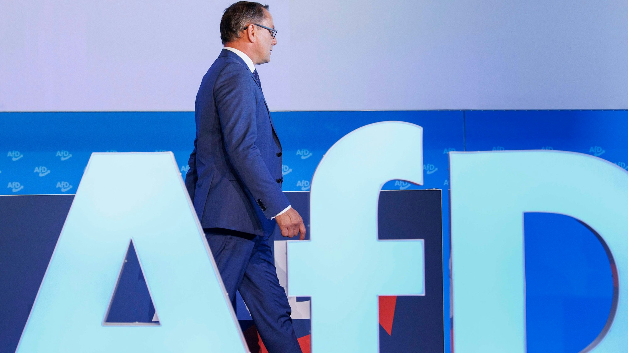 30.07.2023, Sachsen-Anhalt, Magdeburg: Tino Chrupalla, AfD-Bundesvorsitzender und Fraktionsvorsitzender der AfD, geht hinter dem AfD-Parteilogo vor der Fortsetzung der Europawahlversammlung in der Messe Magdeburg. Foto: Carsten Koall/dpa +++ dpa-Bildfunk +++