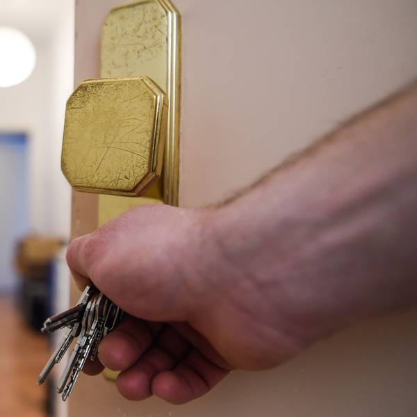 Ein Mann schließt eine Wohnungstür auf und öffnet sie.