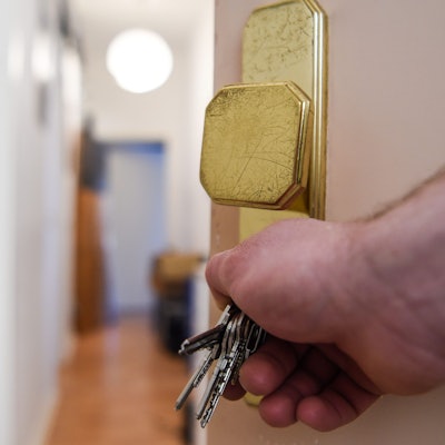 Ein Mann schließt eine Wohnungstür auf und öffnet sie.