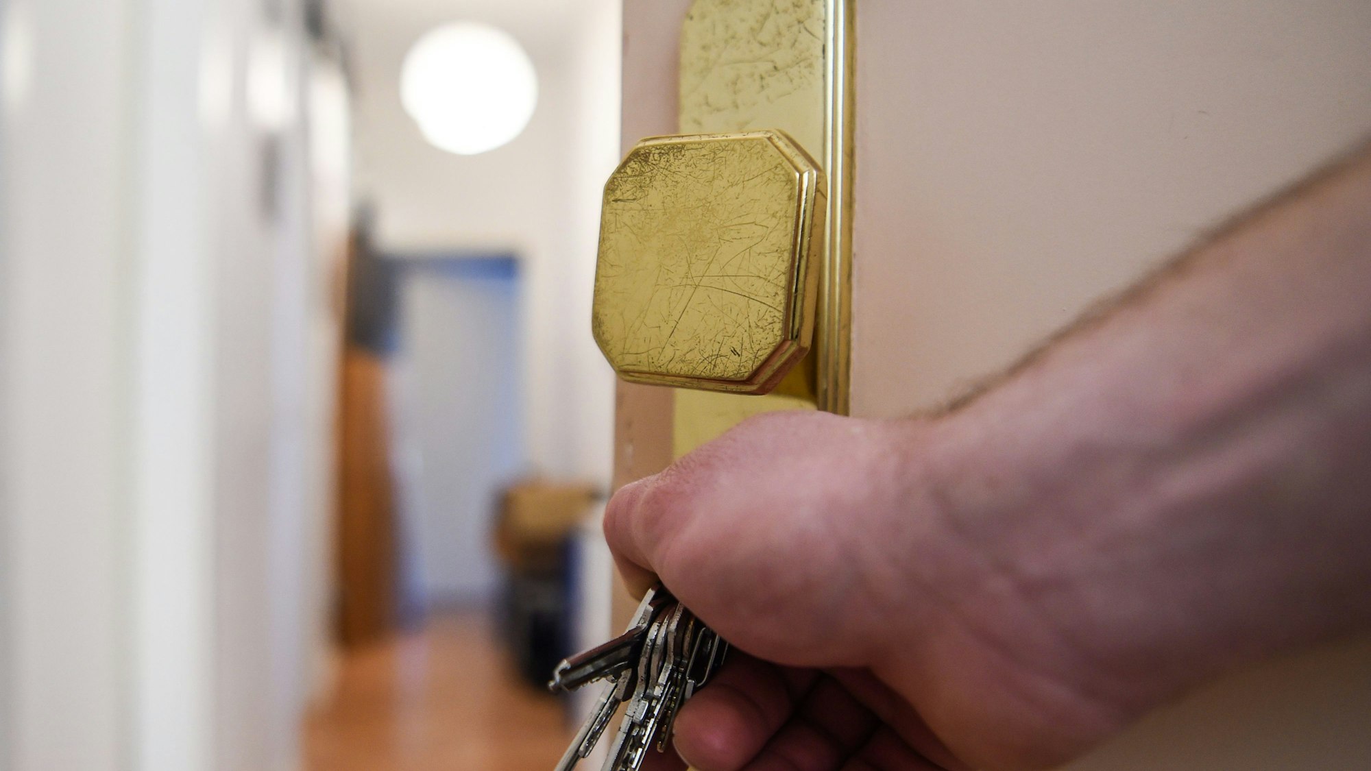 Ein Mann schließt eine Wohnungstür auf.