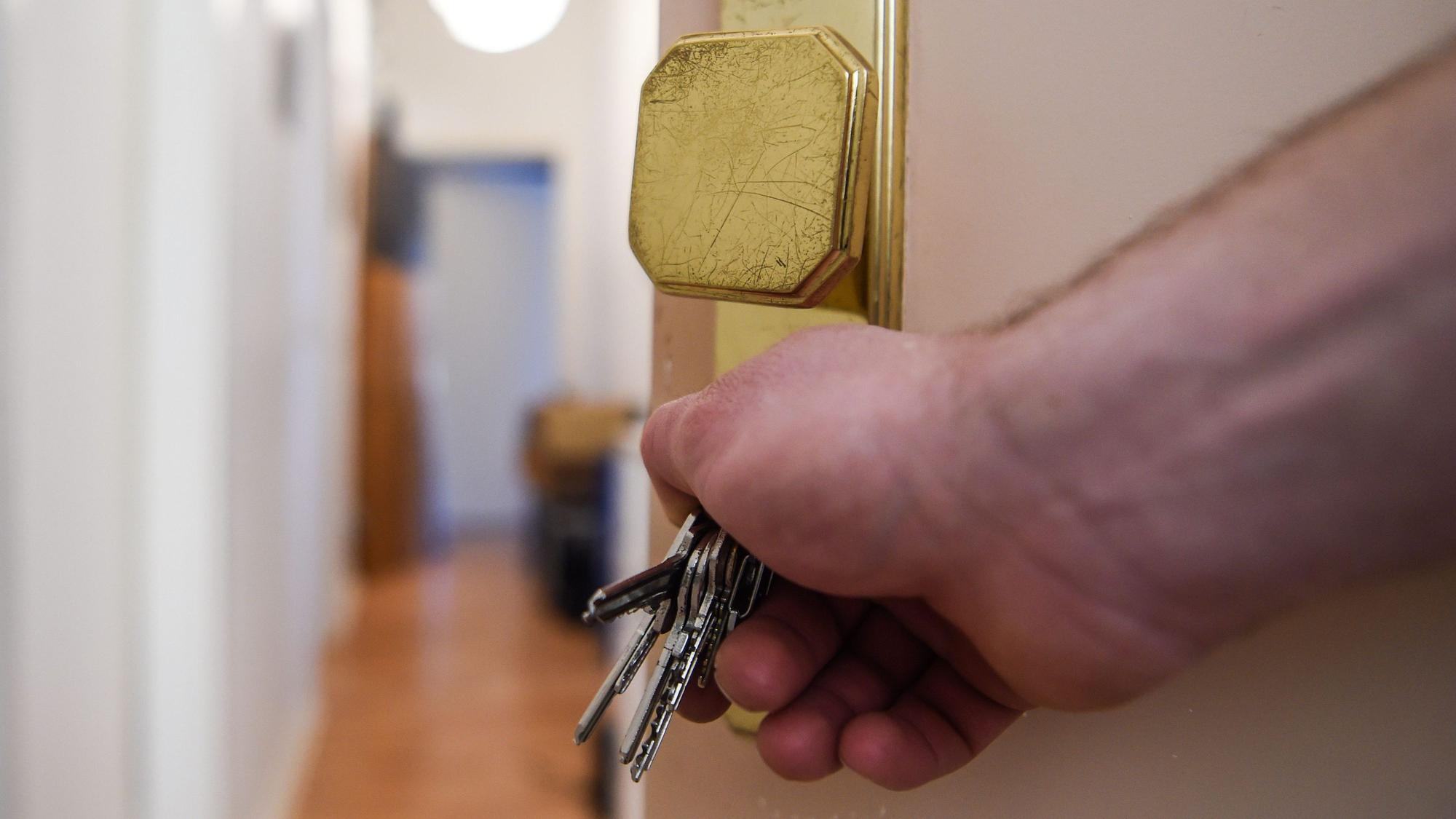 Ein Mann schließt eine Wohnungstür auf und öffnet sie.