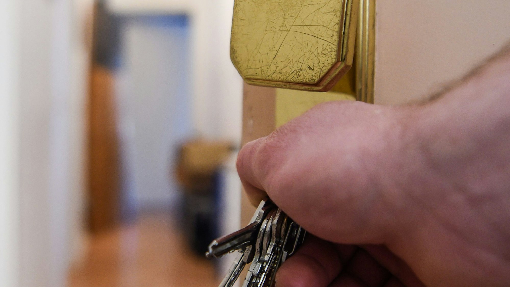 Ein Mann schließt eine Wohnungstür auf und öffnet sie.