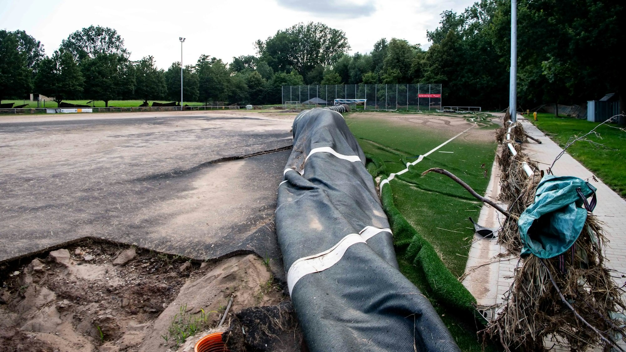 Das Foto zeigt einen vom Hochwasser zerstörten Kunstrasenplatz.