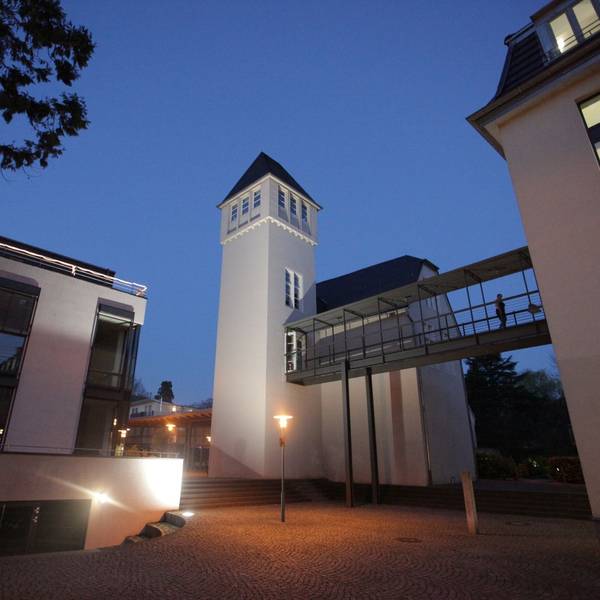 Historische und moderne Gebäude stehen auf dem Campus-Gelände, das in der Dämmerung beleuchtet ist,