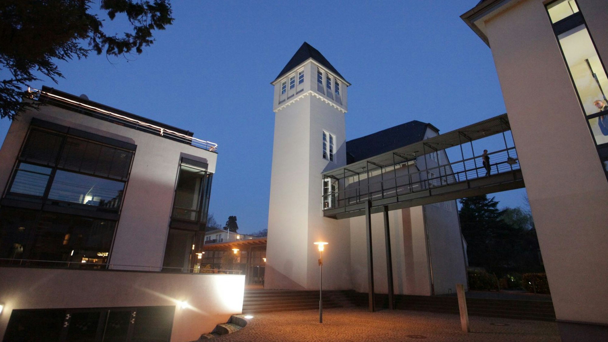 Historische und moderne Gebäude stehen auf dem Campus-Gelände, das in der Dämmerung beleuchtet ist,