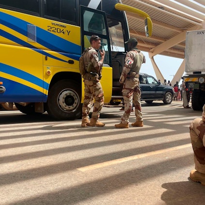 Französische Soldaten stehen neben einem Bus, der französische Staatsangehörige zum Flughafen bringt, von wo sie mit einem Militärflugzeug nach Frankreich geflogen werden sollen.