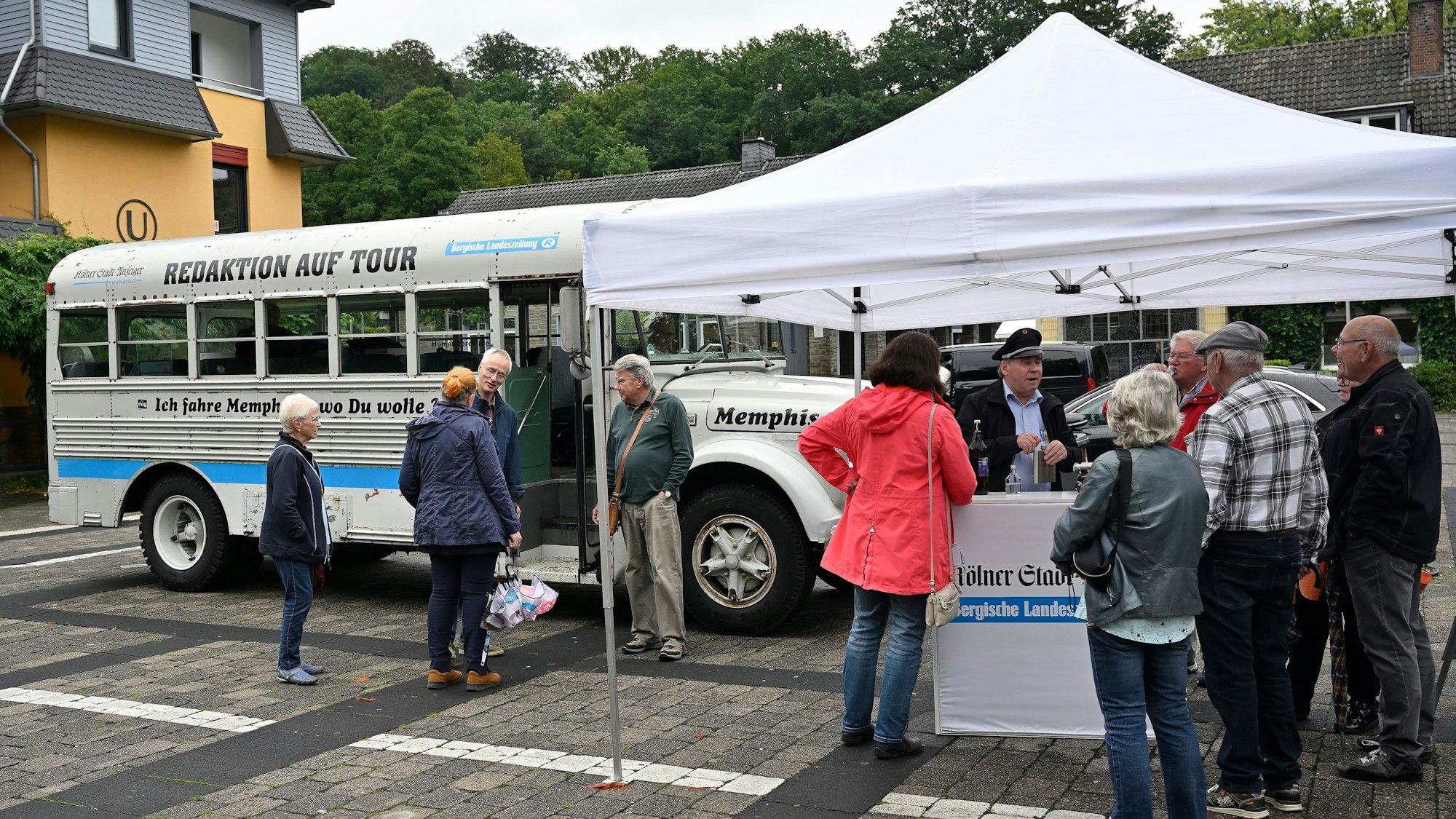Menschen stehen um einen historischen Bus und einen Infostand, auf dem zu lesen ist: Bergische Landeszeitung und Kölner Stadt-Anzeiger.