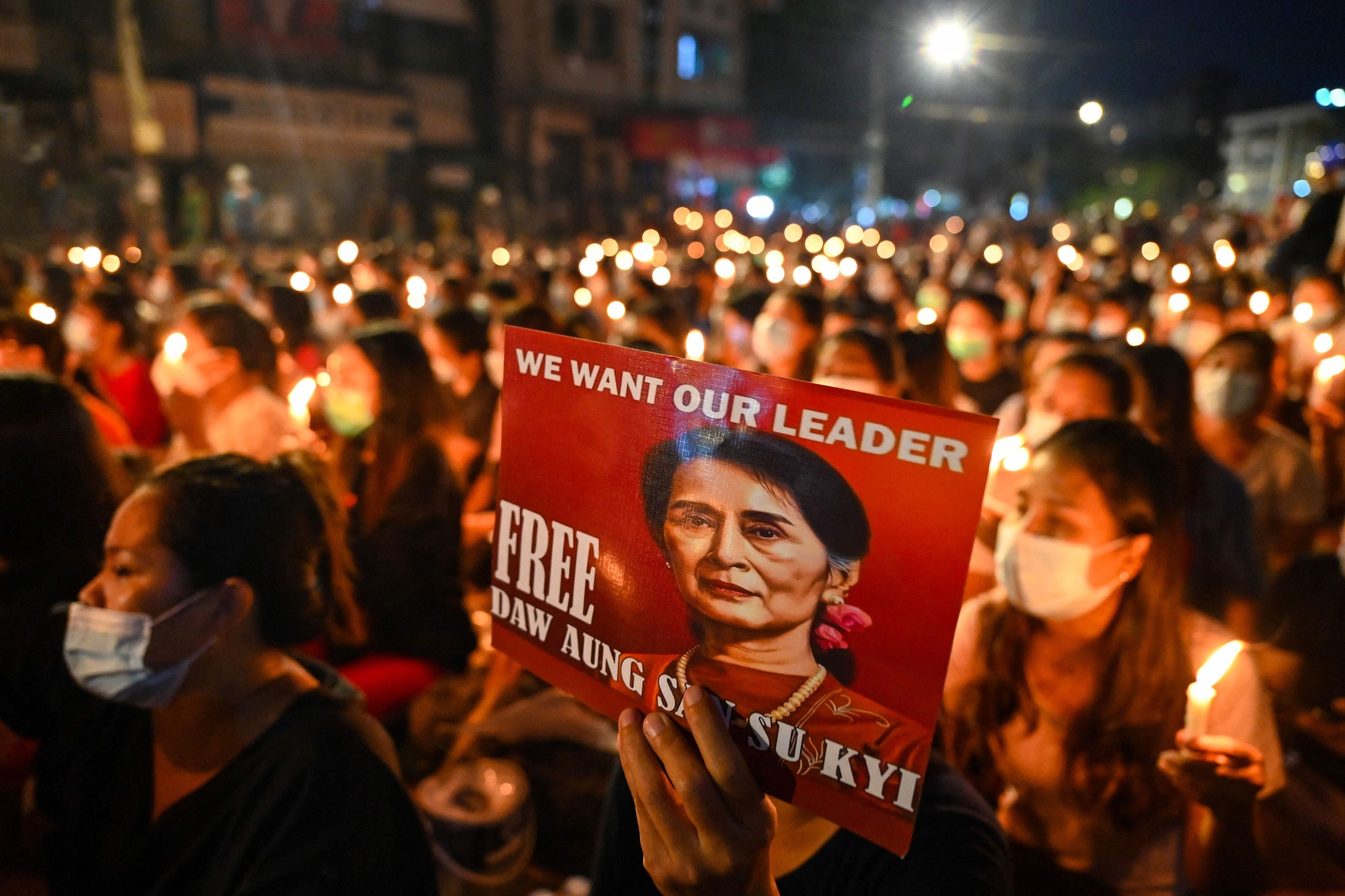 (FILES) A protester holds a poster with an image of detained civilian leader Aung San Suu Kyi during a candlelight vigil to honour those who have died during demonstrations against the military coup in Yangon on March 13, 2021. Myanmar civilian leader Aung San Suu Kyi, who has been in detention since she was ousted in a 2021 military coup, will be pardoned in a junta amnesty of more than 7000 prisoners to mark Buddhist Lent, state media said on August 1, 2023. (Photo by AFP)