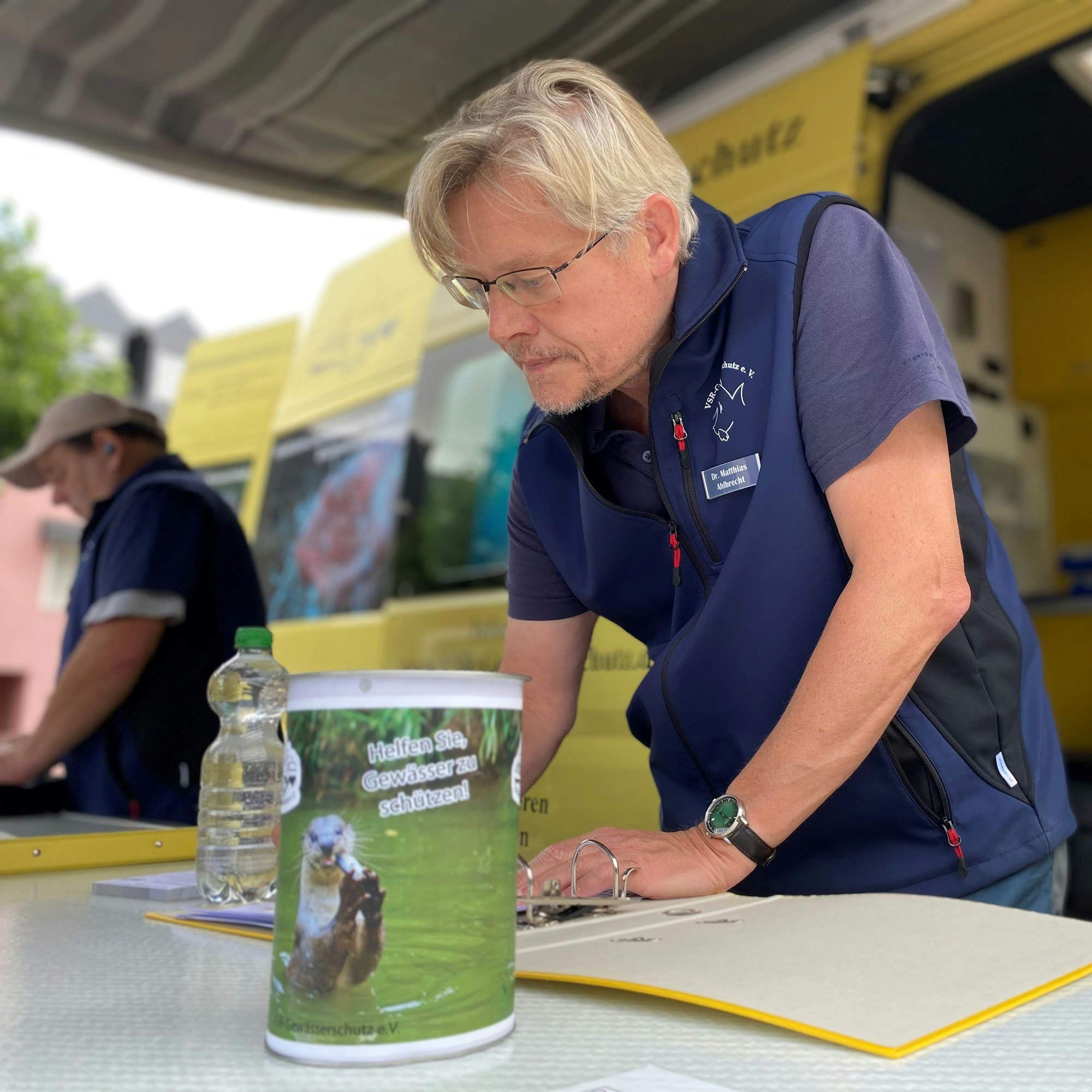 Vor einem gelben Transporter stehen Experte Dr. Matthias Ahlbrecht und der ehrenamtliche Helfer Frank Sombrowski und beraten Interessenten.