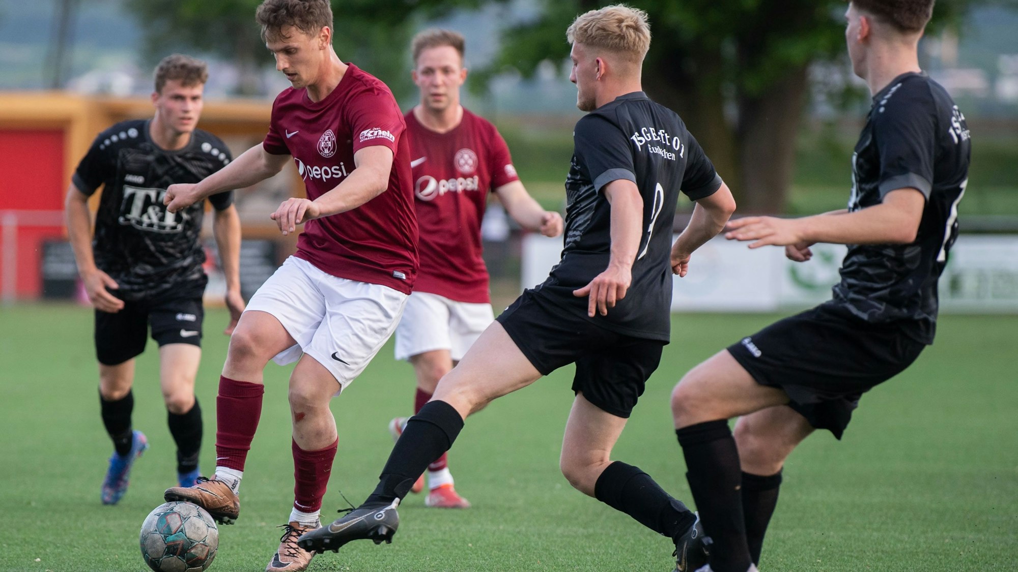 Spielszene aus der Partie TuS Zülpich gegen JSG Erft 01. Ein Zülpicher Spieler hat den Ball und wird von einem Erft-Akteur attackiert.