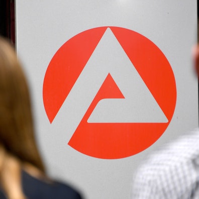Zwei Personen stehen vor dem Logo der Agentur für Arbeit.