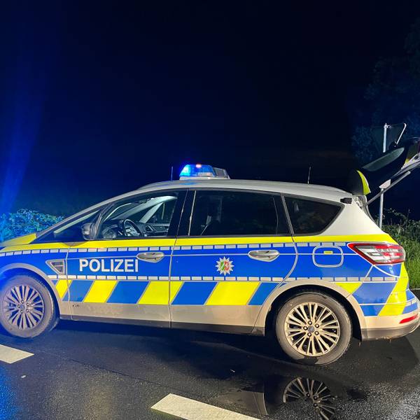 Ein Streifenwagen steht mit eingeschaltetem Blaulicht bei Nacht an einer Kreuzung.