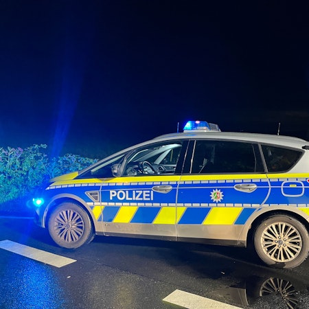 Ein Streifenwagen steht mit eingeschaltetem Blaulicht bei Nacht an einer Kreuzung.