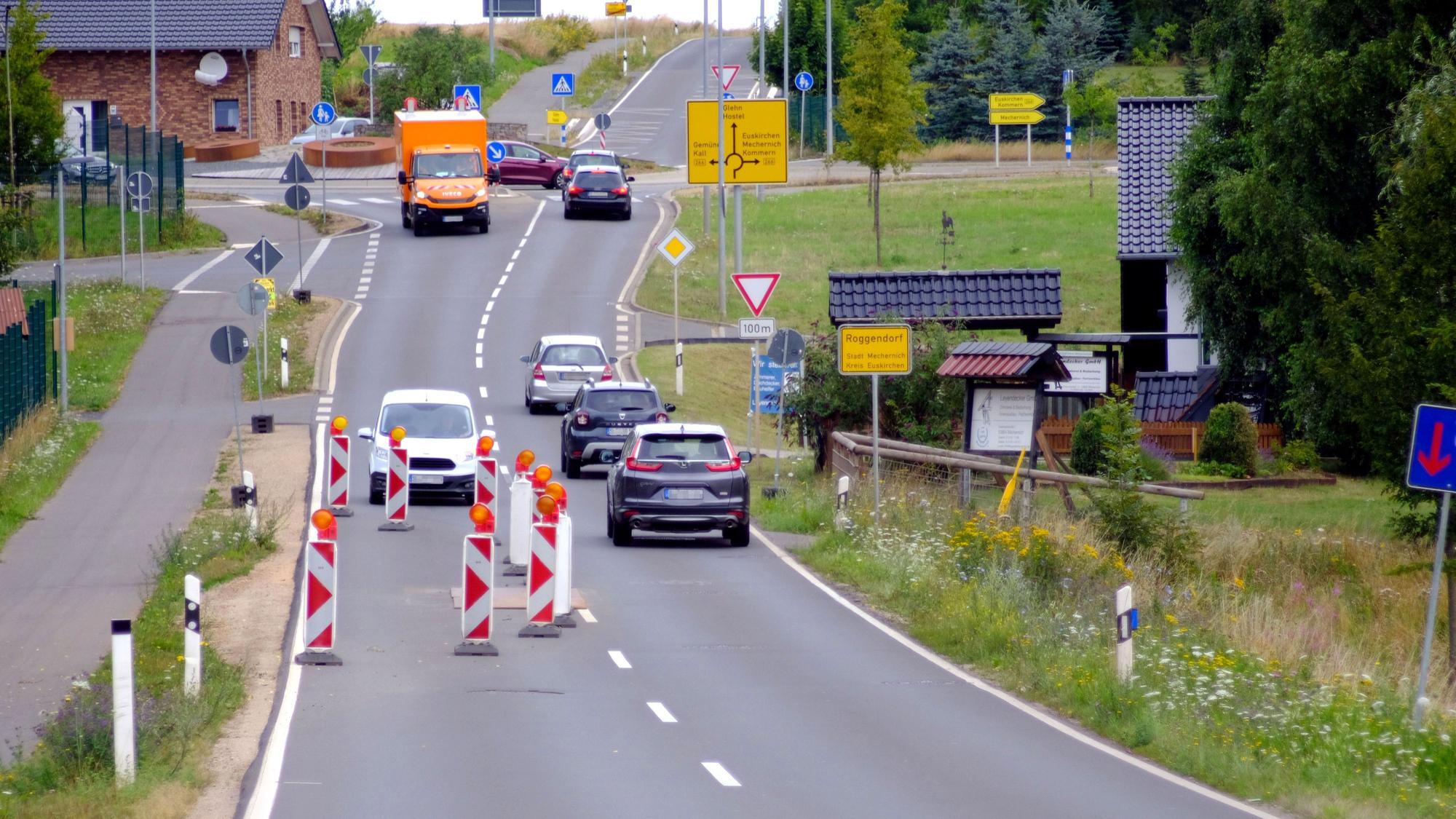 Die Fahrbahn einer Straße ist auf einer Seite mit Warnbaken abgesperrt, der Gegenverkehr muss warten.