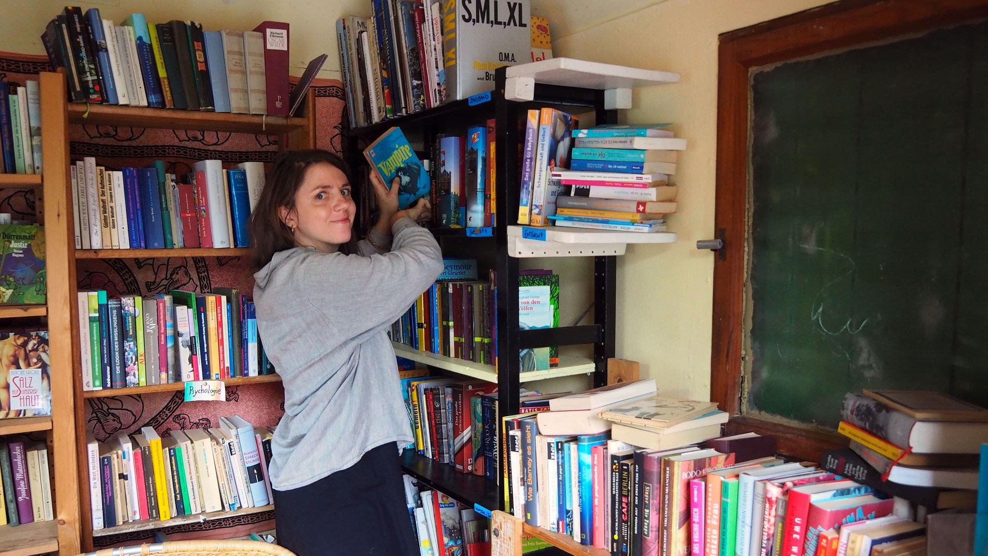 Eine Frau sortiert die Bücher im Bauwagen.