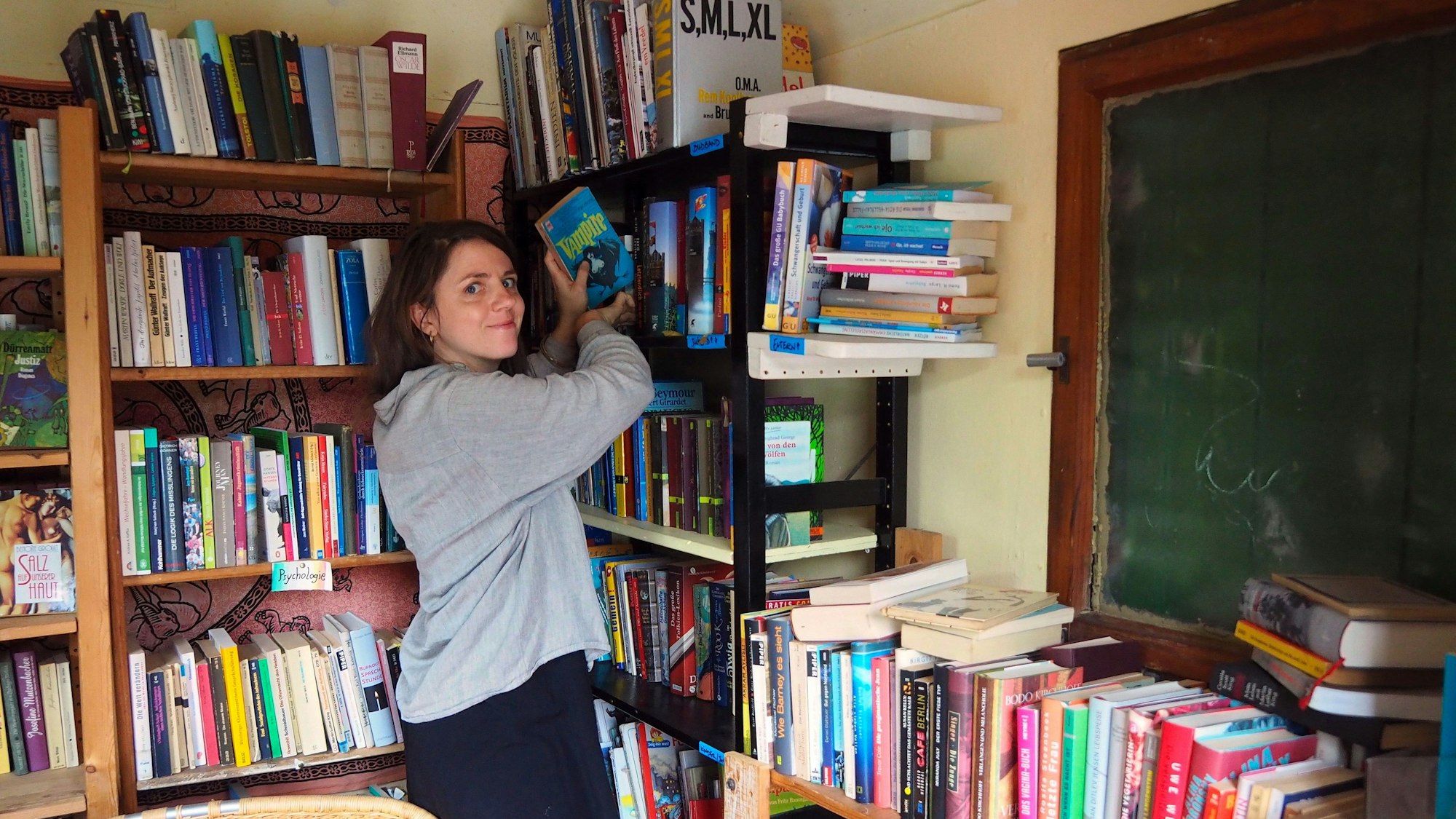 Eine Frau sortiert die Bücher im Bauwagen.