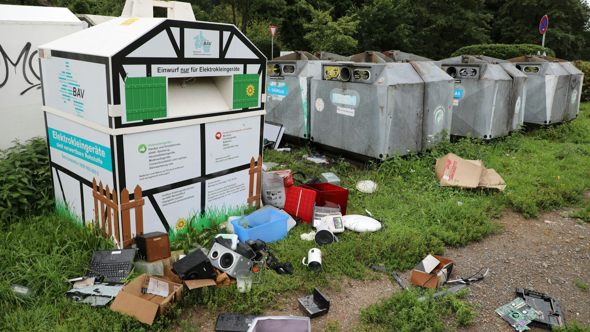 Müll liegt vor und neben Recycling-Containern.