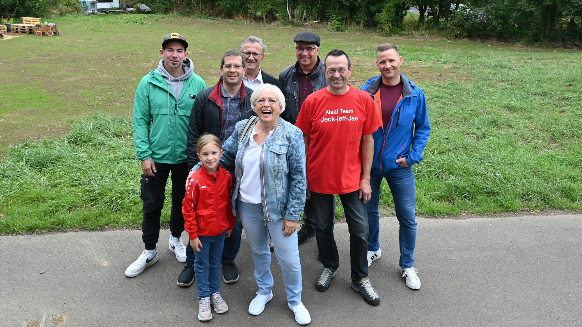 Eine Gruppe Menschen steht vor einer Wiese. Dort hat bis zur Flut das Vereinsheim des Gemünder Karnevalsvereins gestanden.