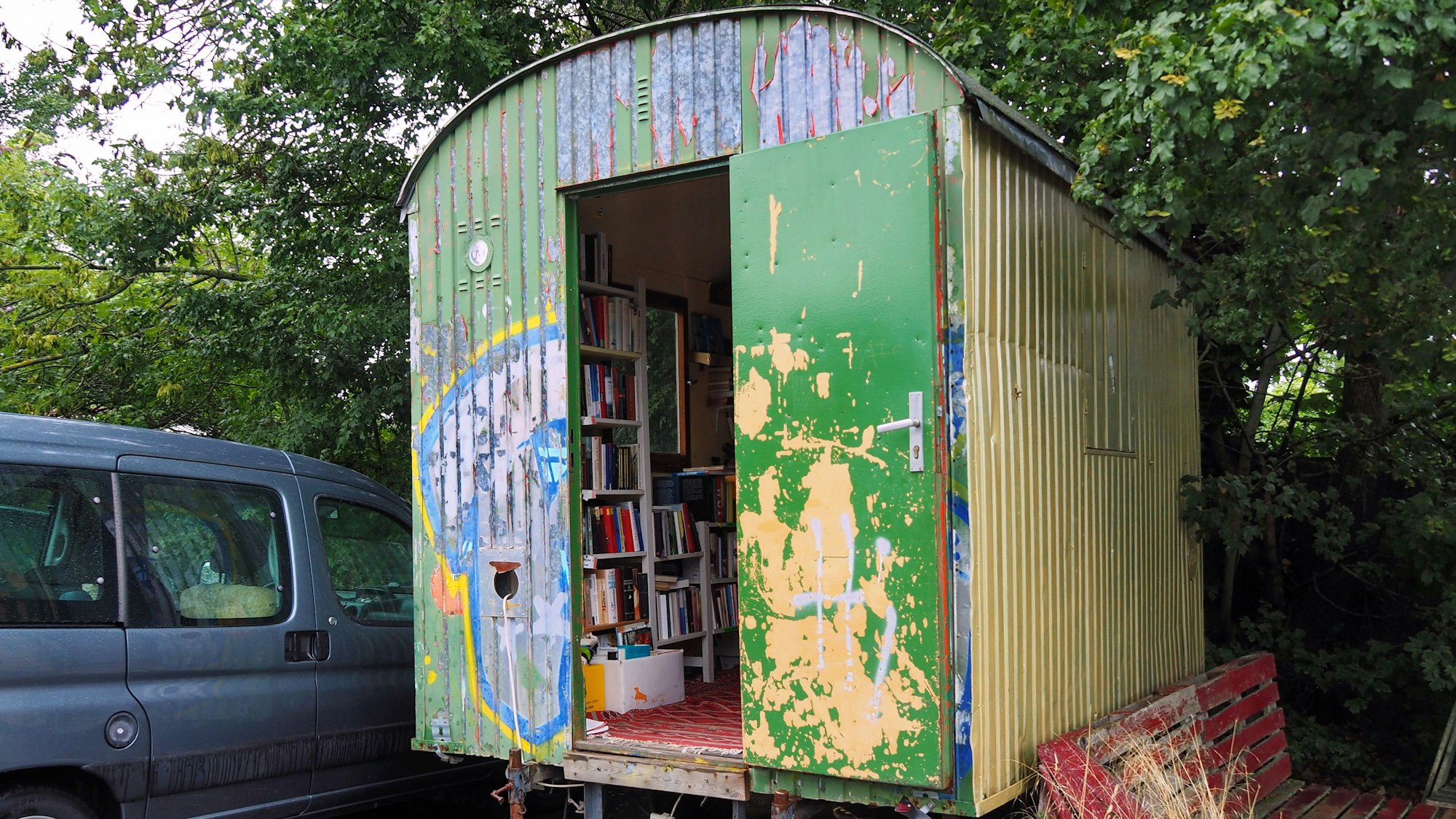 Ein Bauwagen steht unter einem Baum.