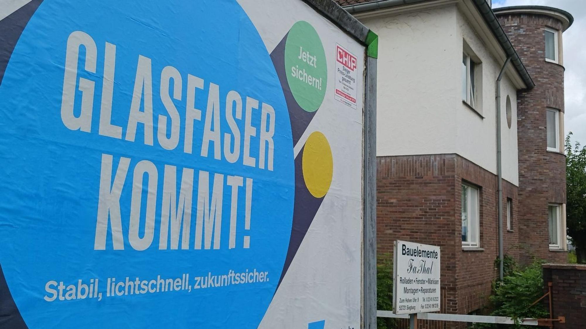 Ein Werbeplakat der Firma Deutsche-Glasfaser wirbt an einer Straße in Siegburg für Glasfaseranschlüsse