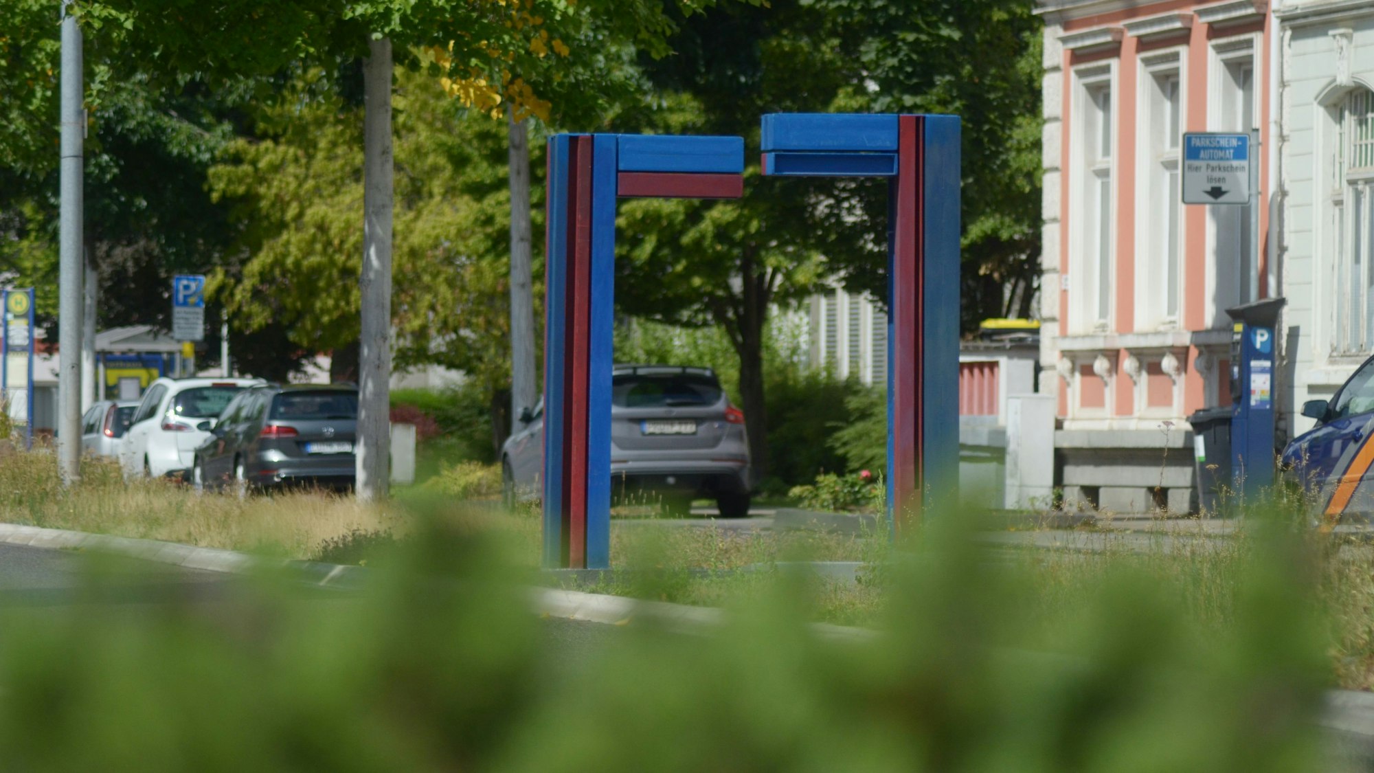 Das Bild zeigt eine blau-rote Skulptur an einer Straße in Euskirchen.
